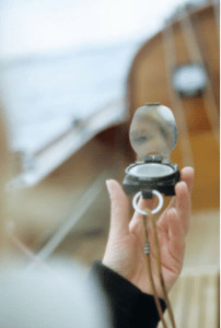 A magnetic compass in a boaters hand, used to measure a boats course and direction.